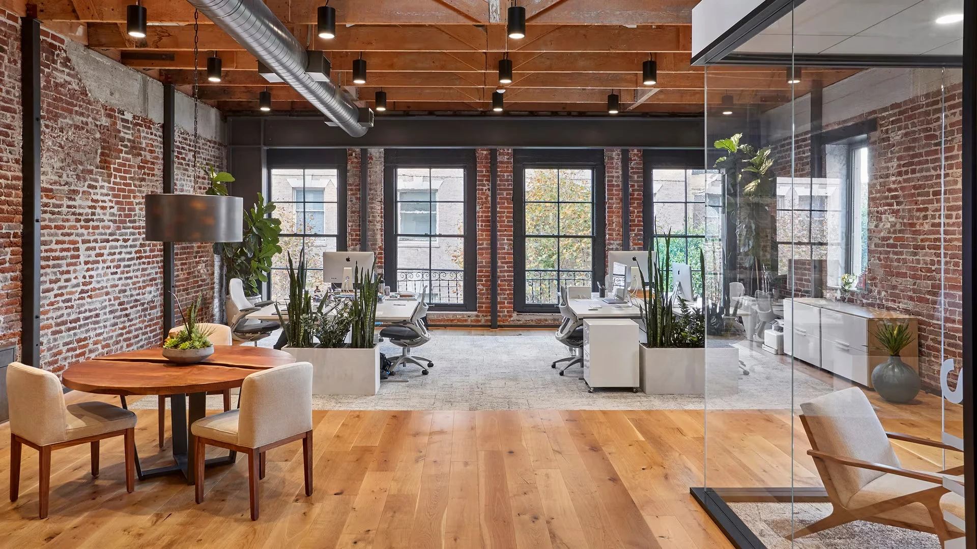 A bright, open office with brick walls, timber ceilings and collaborative workspaces